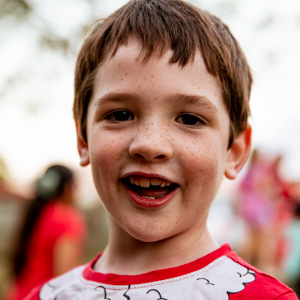 Boy wearing a Christmas shirt smiling and looking at the camera.